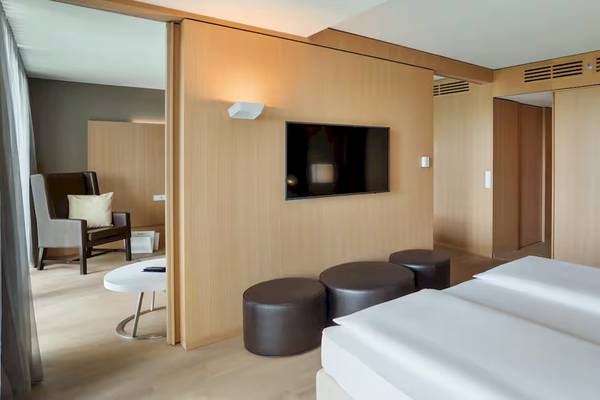 Doppelzimmer im DoubleTree by Hilton Vienna Schonbrunn mit Fernseher an der Wand und drei Hockern.