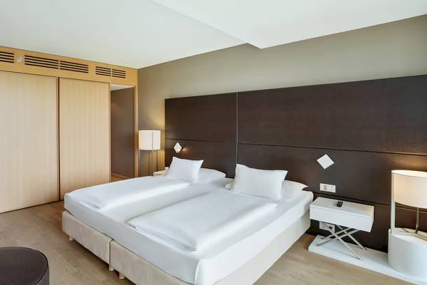 Doppelzimmer im DoubleTree by Hilton Vienna Schonbrunn mit zwei Betten, Nachttischen und Lampen.