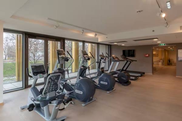 Fitnesscenter im DoubleTree by Hilton Wien Schonbrunn mit verschiedenen Trainingsgeräten und großen Fenstern.