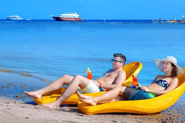Ein Paar liegt auf gelben Strandliegen am Strand des Pickalbatros Palace Resort in Hurghada.