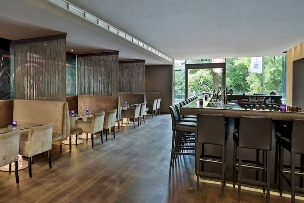 Innenansicht des Restaurants im DoubleTree by Hilton Vienna Schonbrunn mit Sitzgelegenheiten und einer Bar.