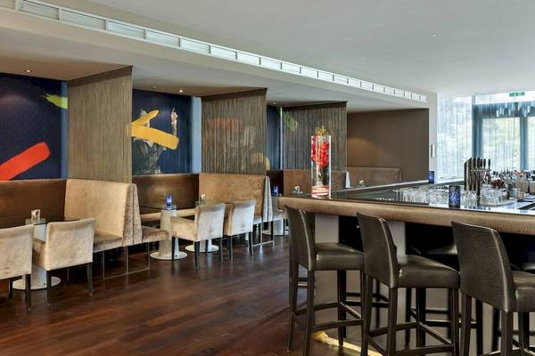 Innenbereich des DoubleTree by Hilton Vienna Schonbrunn mit Bar, Sitzbereich und Kunst an den Wänden.