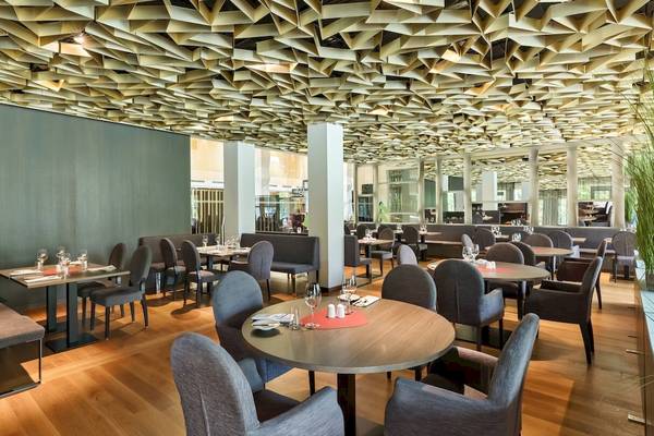 Innenansicht des Restaurants im DoubleTree by Hilton Wien Schonbrunn mit modernen Möbeln und geometrischen Deckenverkleidungen.