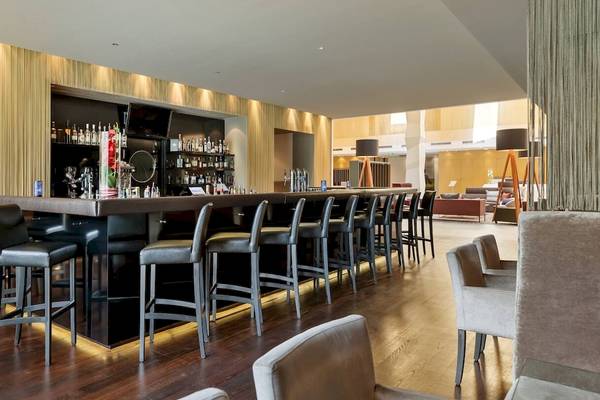 Barbereich im DoubleTree by Hilton Vienna Schonbrunn Hotel mit Barhockern und Sitzgelegenheiten.