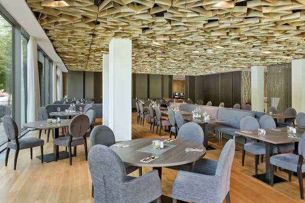 Innenraum des Restaurants im DoubleTree by Hilton Vienna Schonbrunn mit modernen Möbeln und geometrischer Deckengestaltung.