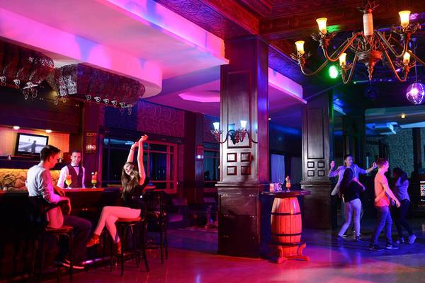 Innenansicht der Bar im Pickalbatros Palace Resort, Hurghada, mit Gästen, Kronleuchter und bunten Lichtern.