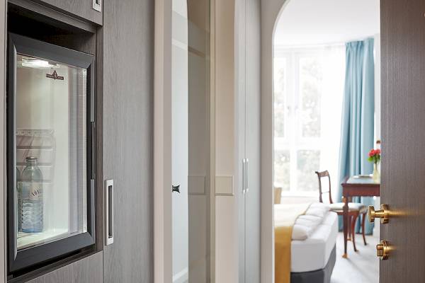 Zimmer im Living Hotel Kaiser Franz Joseph mit einem offenen Kühlschrank, der eine Flasche Wasser enthält.