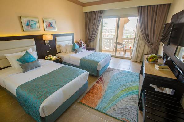 Doppelzimmer mit zwei Betten, einem Tisch und einem Balkon im Pickalbatros Palace Resort, Hurghada.