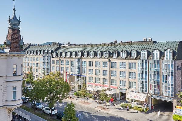 Außenansicht des Living Hotel Kaiser Franz Joseph mit vielen Fenstern und Bäumen davor