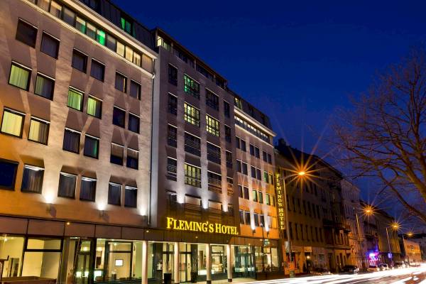 Außenansicht des Flemings Hotel Wien-Stadthalle bei Nacht mit Beleuchtung und Straße im Vordergrund.