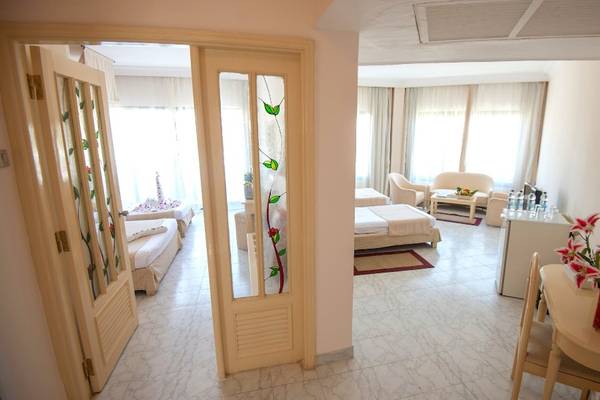 Innenansicht des Grand Hotel Hurghada mit Schlafzimmer, Bett, Tisch, Stuhl und Vase mit Blumen.