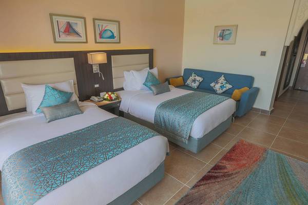 Doppelzimmer mit Schlafsofa im Pickalbatros Palace Resort, Hurghada mit zwei Betten, Sofa, Nachttischen und gerahmten Bildern an der Wand.
