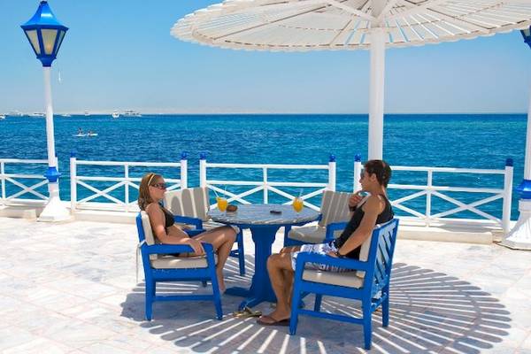 Zwei Gäste sitzen an einem runden Tisch auf der Terrasse des Grand Hotel Hurghada mit Blick auf das Meer.