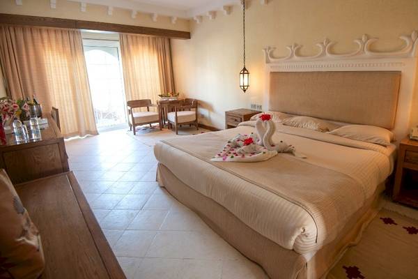 Schlafzimmer im Grand Hotel Hurghada mit großem Bett, Dekor und Nachttischen.