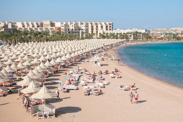 Luftaufnahme vom Strand des Grand Hotel Hurghada mit vielen Liegen und Sonnenschirmen.