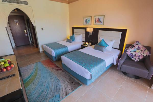 Doppelbett-Zimmer im Pickalbatros Palace Resort, Hurghada, mit zwei Betten, Tisch, Stuhl und Früchten.