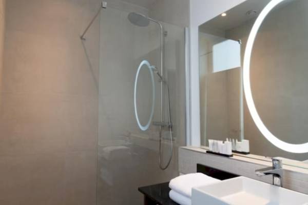 Ein Badezimmer mit einer Glasdusche, einem Waschbecken und einem großen Spiegel.