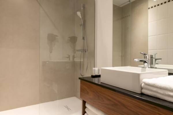 Badezimmer im Crowne Plaza Paris République mit ebenerdiger Dusche, Waschbecken und Spiegel.