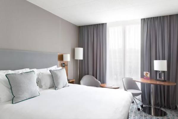Ein elegantes Hotelzimmer im Crowne Plaza Paris République mit einem Bett, Stühlen und Tisch.