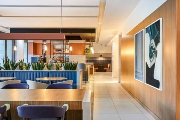 Innenbereich des Crowne Plaza Paris République Hotels mit Sitzbereichen, Tischen und Kunstwerken an der Wand.