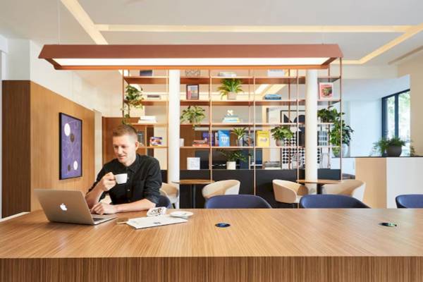 Ein Mann sitzt mit Laptop und Kaffee in einem Hotellobby.
