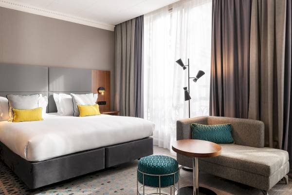 Hotelzimmer im Crowne Plaza Paris République mit Bett, Kissen und Möbeln.