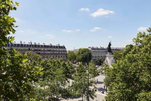 Aussicht von Crowne Plaza Paris République auf einen Stadtplatz mit Bäumen und Gebäuden.