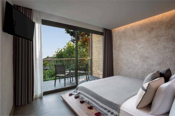 Schlafzimmer mit Balkon und Bett im Club Marvy Hotel, Blick auf Terrasse mit Stühlen und Bäumen