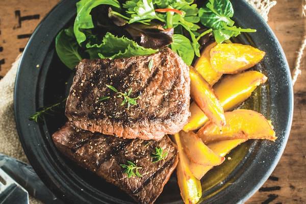 Ein Teller mit gegrilltem Steak und Pfirsichscheiben im Club Marvy Hotel.
