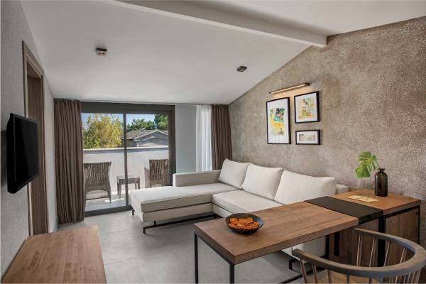 Inneneinrichtung eines Zimmers im Club Marvy Hotel mit Sofa, Tisch und Fernseher.