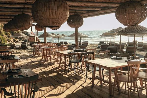 Strandrestaurant des Club Marvy mit Tischen und Stühlen unter Bambuslampen am Meer