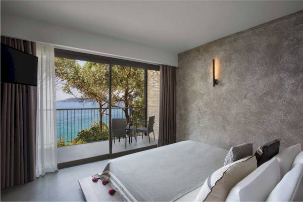 Schlafzimmer mit Meerblick im Club Marvy Hotel, zeigt ein Bett, Balkon mit Sitzmöbeln und Ausblick auf das Meer.
