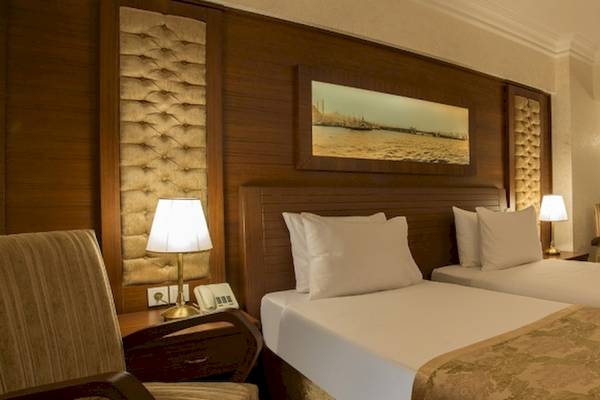 Doppelbett-Zimmer im Yigitalp Hotel mit zwei Betten, Lampen, Stühle und Schreibtisch.