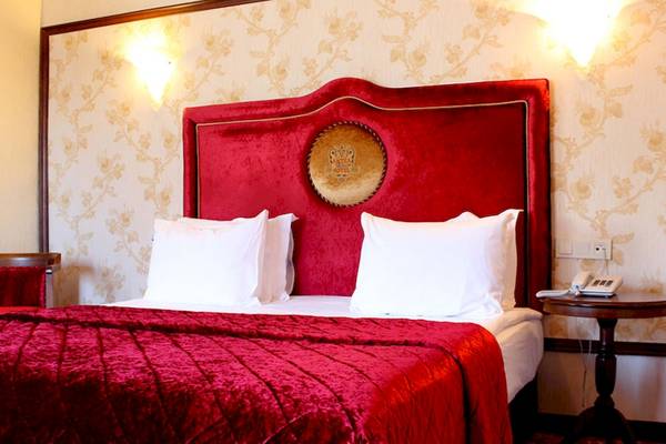 Schlafzimmer im Antea Palace Hotel & Spa mit rotem Kopfteil, weißen Kissen und Nachttisch