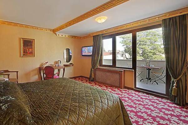 Schlafzimmer im Antea Palace Hotel & Spa mit grünem Kopfteil, einem Bett, einem Tisch und einem Fernseher.