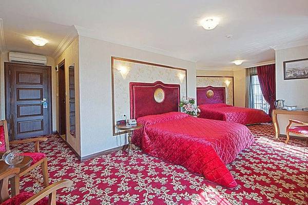 Zwei Betten in einem Schlafzimmer des Antea Palace Hotel & Spa mit rotem Teppich und Möbeln.