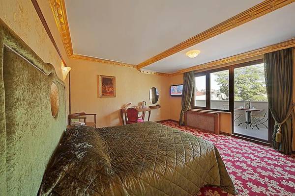 Schlafzimmer im Antea Palace Hotel & Spa mit großem Bett, grüner Bettwäsche und Balkonzugang