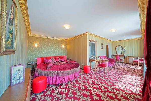 Luxus Schlafzimmer im Antea Palace Hotel & Spa mit rotem Bett und goldenen Wandverzierungen.
