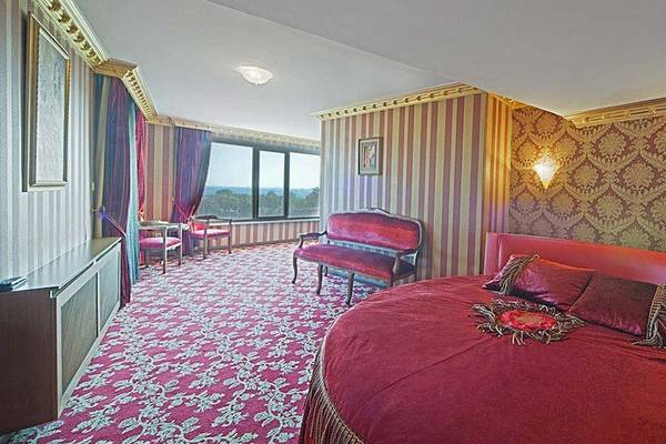 Das Schlafzimmer im Antea Palace Hotel mit rotem Bett, goldenen Wandverzierungen und großem Fenster.