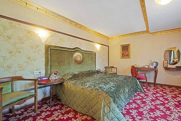 Schlafzimmer im Antea Palace Hotel mit grünem Bett und rotem Teppich
