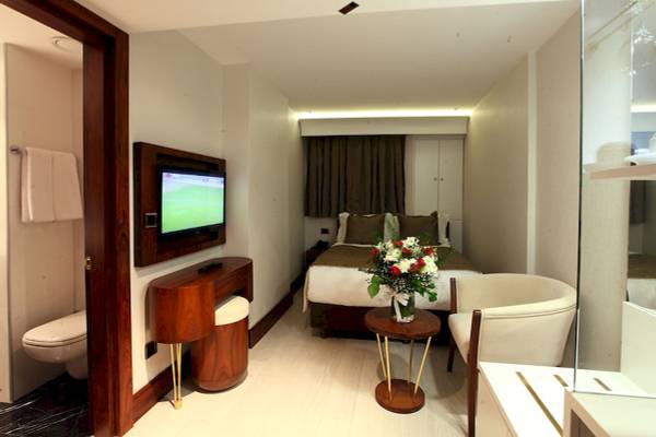 Zimmer im Victory Hotel & Spa Istanbul mit Bett, Fernseher, Tisch und Blumen.
