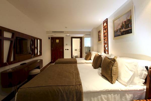 Schlafzimmer im Victory Hotel & Spa Istanbul mit zwei Betten, Fernseher und Kunstwerken an der Wand.
