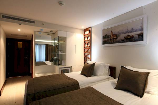Doppelbettzimmer im Victory Hotel & Spa Istanbul mit zwei Betten, Kissen und einem Wandbild.