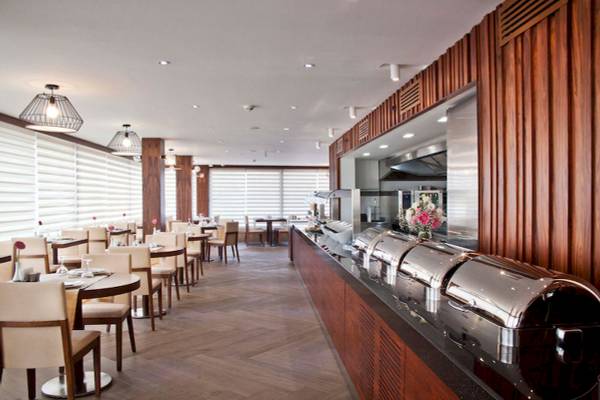 Innenansicht des Restaurants im Victory Hotel & Spa Istanbul mit Holzwänden und gedeckten Tischen.