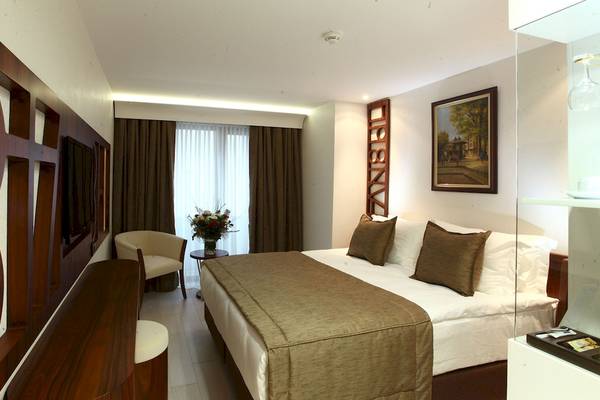 Schlafzimmer im Victory Hotel & Spa Istanbul mit einem Bett, Kissen, einem Tisch mit Blumen und einem Stuhl.