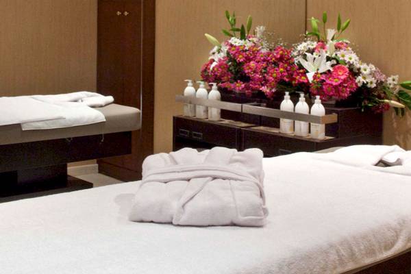 Massageraum im Victory Hotel & Spa Istanbul mit zwei Massagetischen, Handtüchern und einer Blumenvase.