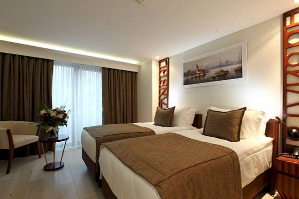 Doppelzimmer im Victory Hotel & Spa Istanbul mit zwei Betten, einem Tisch, einem Stuhl und einem Gemälde an der Wand.