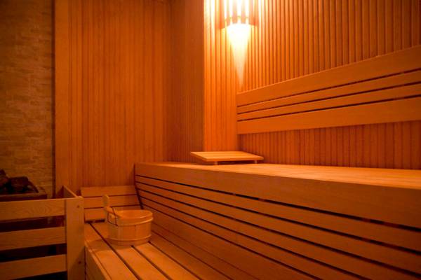 Sauna-Zimmer im Victory Hotel & Spa Istanbul mit Holzbänken, einem Eimer und einer Lampe.