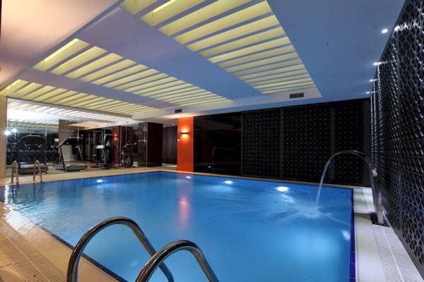 Innenpool des Victory Hotel & Spa Istanbul mit Wasserfontäne und Fitnessgeräten im Hintergrund.