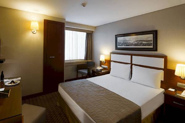 Doppelbettzimmer im Golden City Hotel Istanbul mit Fernseher, Schreibtisch und Fenster.